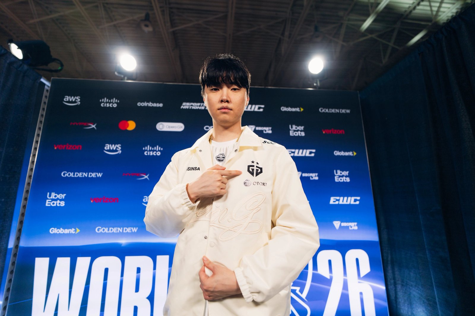 Chovy wearing a Gen.G jacket at a Worlds media backdrop